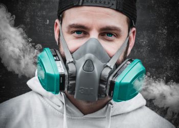 man in white hoodie wearing green gas mask