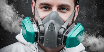 man in white hoodie wearing green gas mask