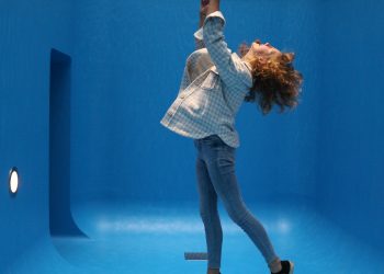 woman in white and black checkered dress shirt and gray pants standing on blue floor
